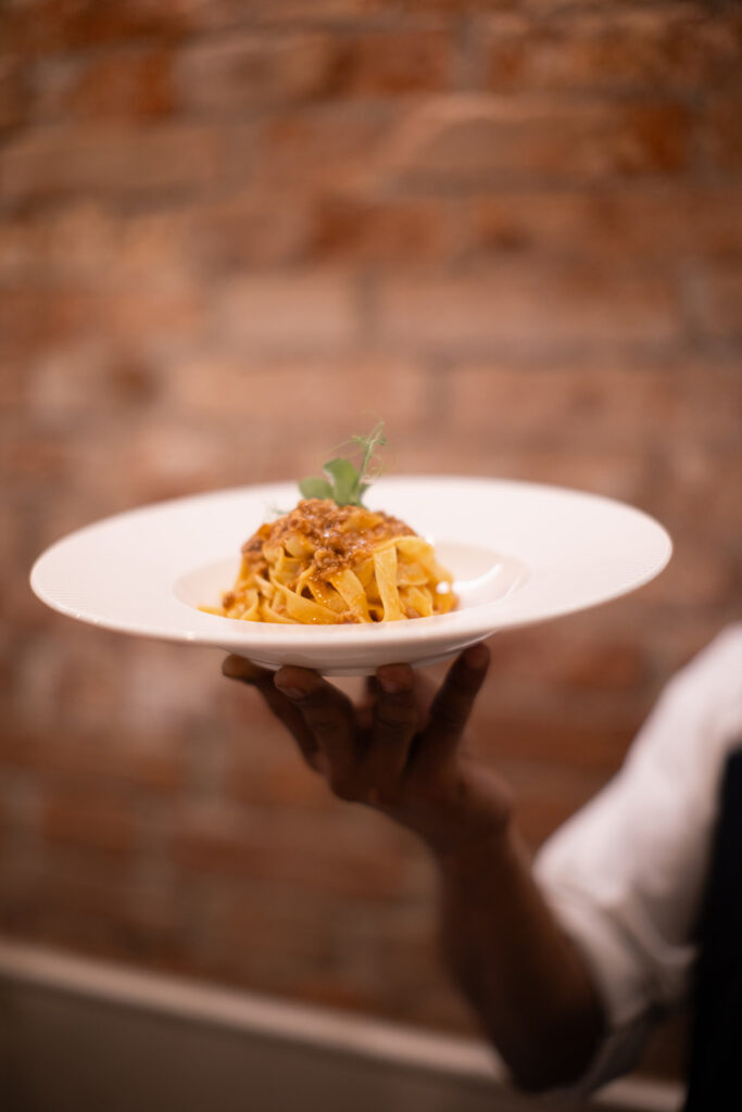 Cameriere serve un piatto di pasta al ragù al ristorante a venezia